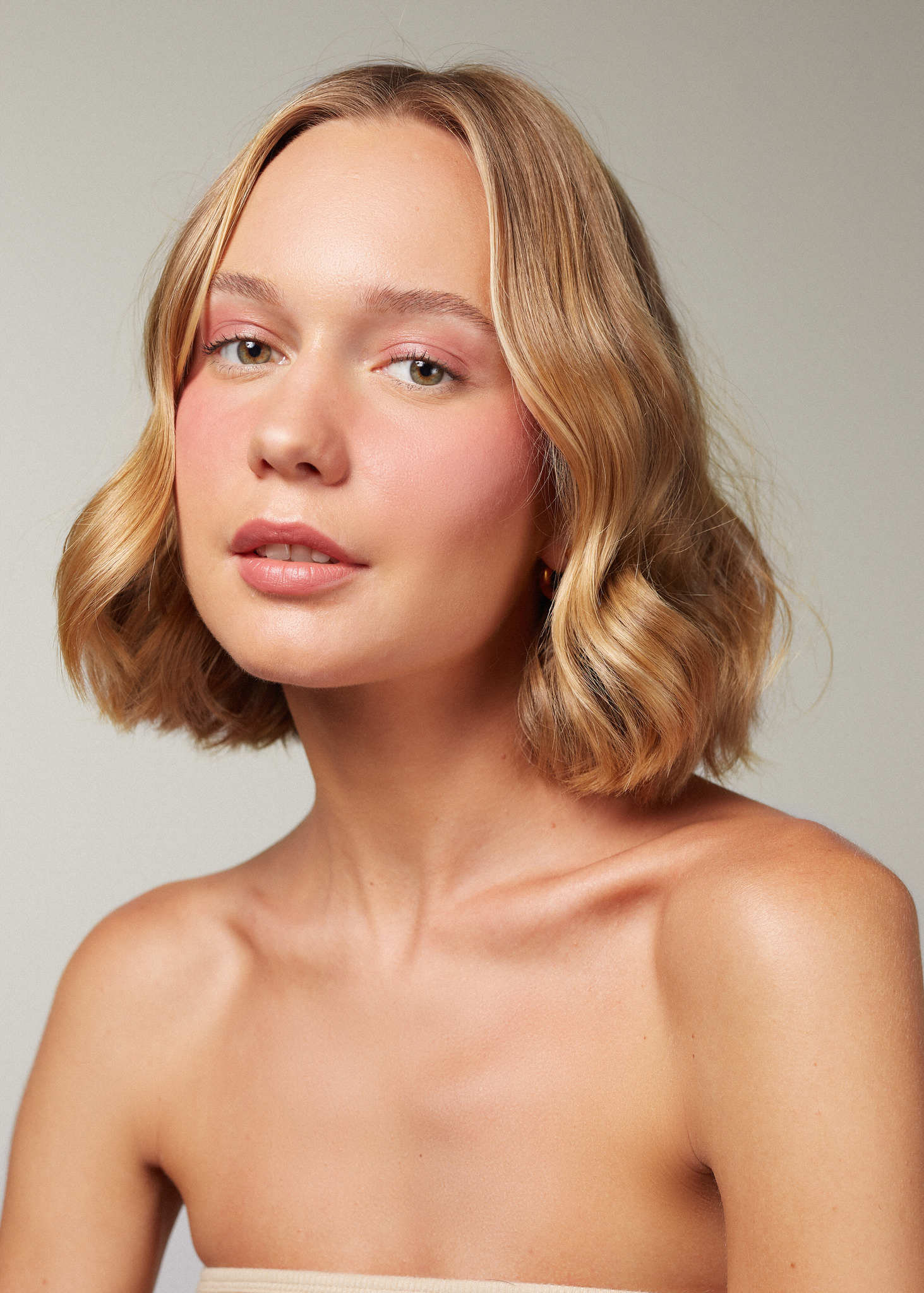 beautiful white woman with glowy skin and rosy cheeks looking a the camera, wearing Canggu balm. 