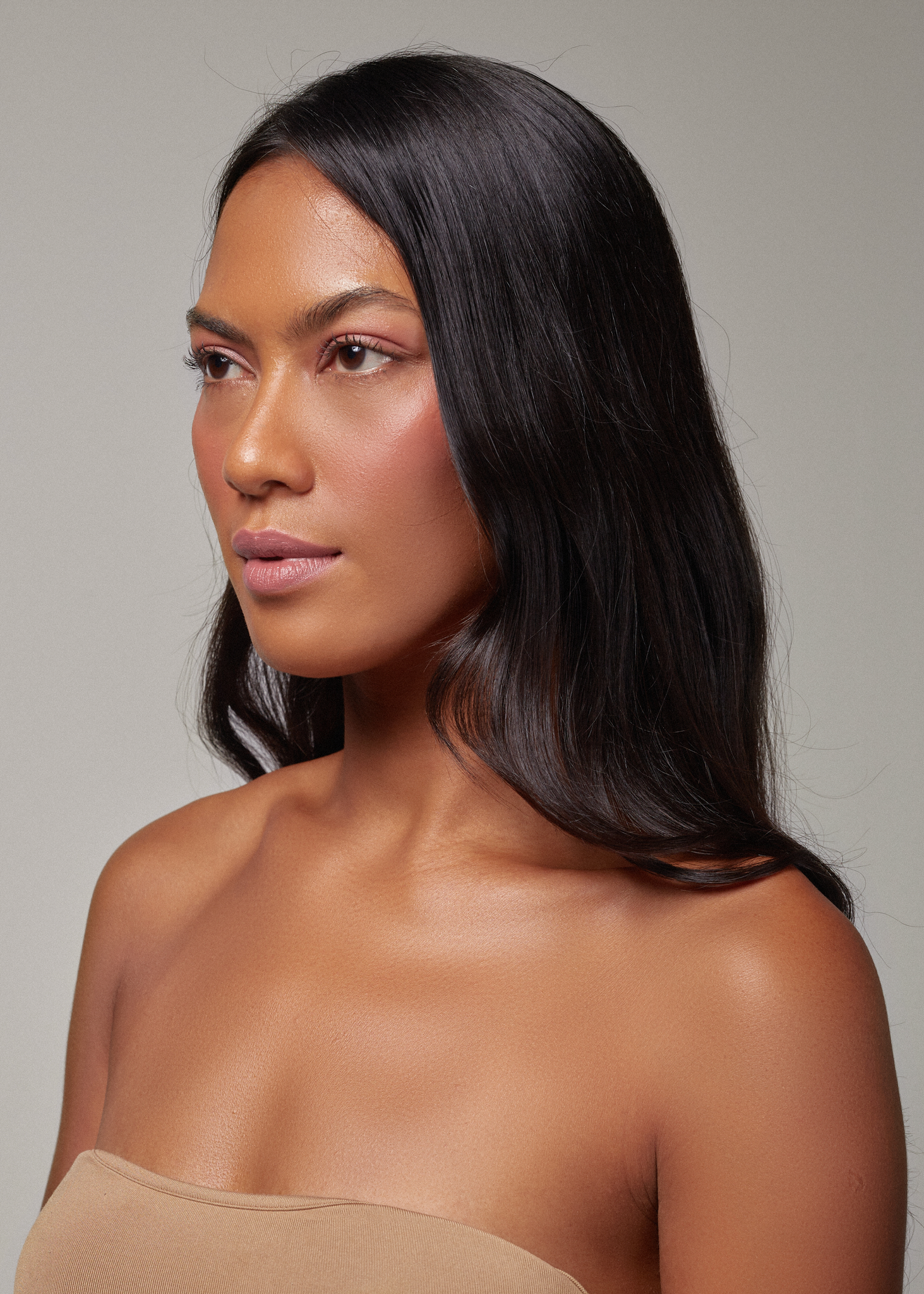 beautiful colored woman with glowy skin looking a the horizon, wearing Canggu balm. 