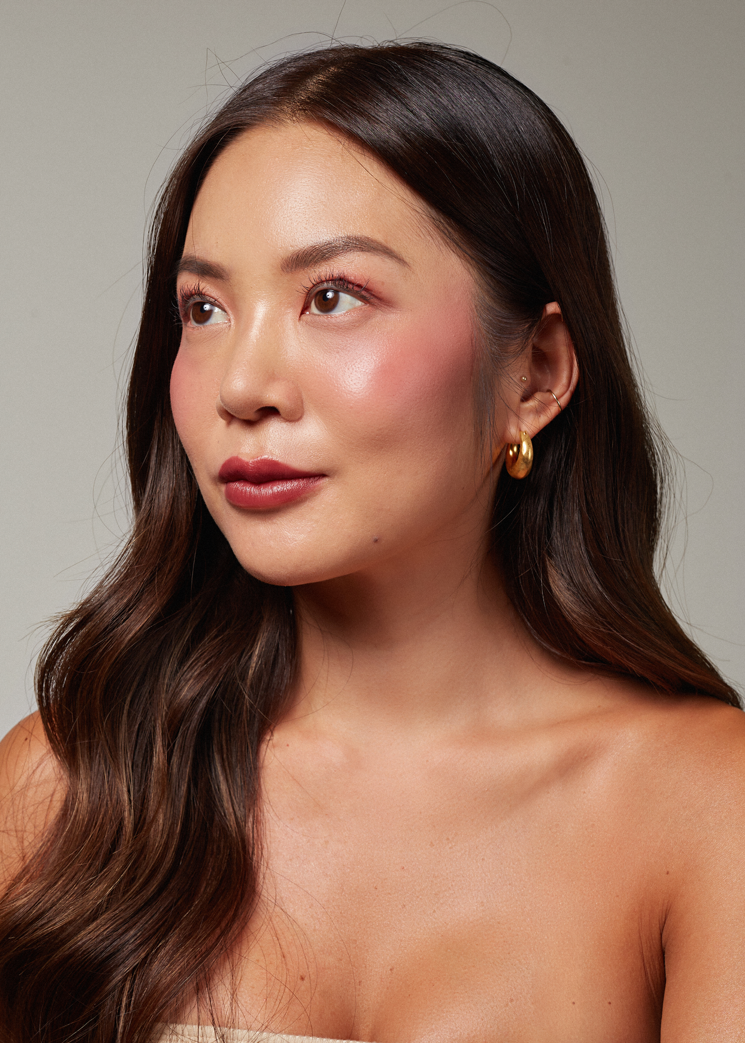 Portrait of an Asian woman, with beautiful glowy skin, wearing the Ubud balm. 